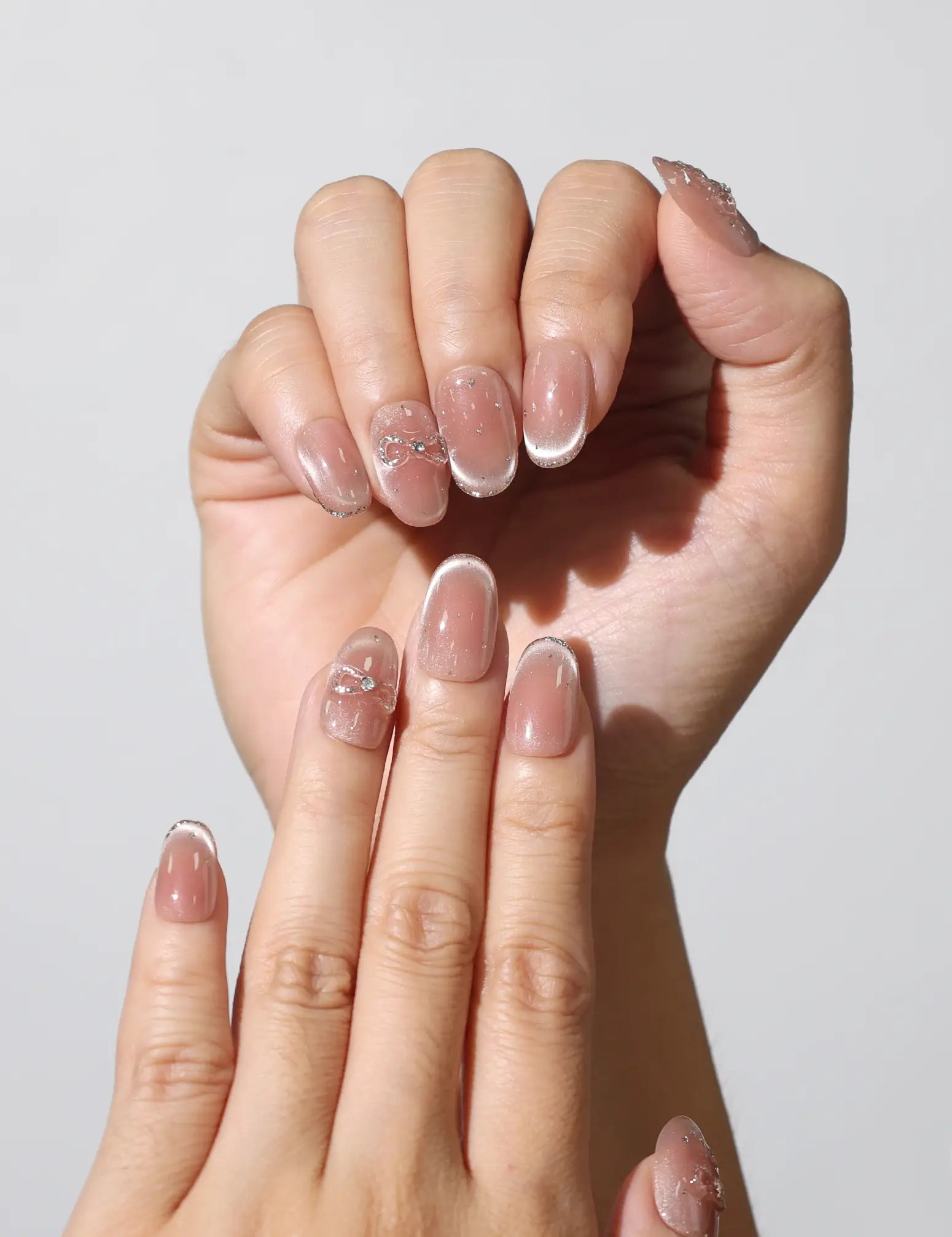 Close-up of Sparkle Allure cat eye handmade press on nails SG with silver bows by Naillover.