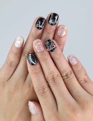 Close-up of Naillover Sweet Goth nails on hand—black and white press on nails with silver accents in a bold coquette style.