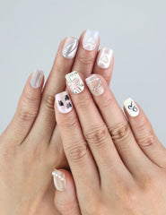 Hand wearing Naillover Sweet Ribbon press on nails in sheer white and lavender with sparkling crystals.