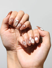 Elegant manicure featuring Tangerine Daisy Shine handmade press on nails SG in tangerine with white flowers.