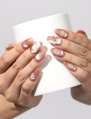 Holding a cup while wearing Tangerine Daisy Shine tangerine floral handmade press on nails by Naillover Singapore.