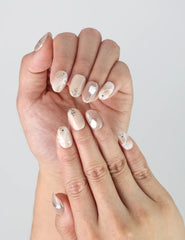 Close-up of Naillover’s handmade nude and gold nails in short oval shape with elegant shimmer