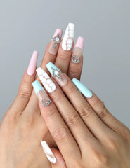 Hand model wearing coffin-shaped press-on nails in pastel pink and blue with crackle texture and starry moon details