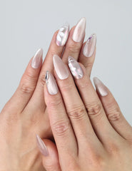 Hand model wearing almond-shaped press-on nails in pastel hues with delicate white floral accents