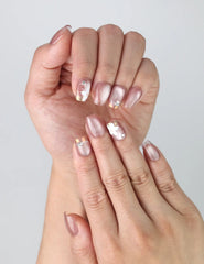 Close-up of Naillover’s handmade square nails featuring blush pink base, sculpted white flowers, and dainty gold and pearl accents