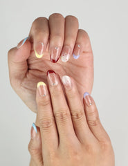 Hand wearing Rainbow Tips handmade press on nails, transparent base with bold colorful glitter tips for a cute and trendy look.