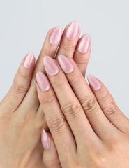 Hand wearing Naillover Soft Mirage press on nails with pink cat eye shimmer in almond shape.