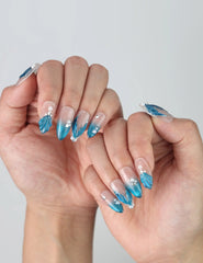 Side angle of glossy blue almond nails featuring iridescent glitter, seashell texture, and dreamy underwater vibes