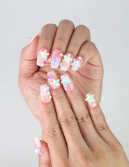 Close-up of Naillover pink press-on nails in glitter finish, featuring playful 3D starfish in coral, aqua, and yellow
