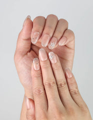 Close-up of Naillover’s handmade press-on nails featuring a nude polish base with fine glitter speckles and subtle gems