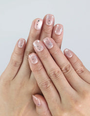 Hand wearing Starlit Blush Naillover press on nails, showing soft pink color and shimmering star details.
