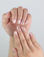 Close-up of short square Naillover Starlit Blush nails on fingers, highlighting dreamy star accents.