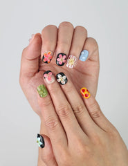 Close-up of handmade squoval nails from Singapore featuring delicate pink floral accents on a nude and black base