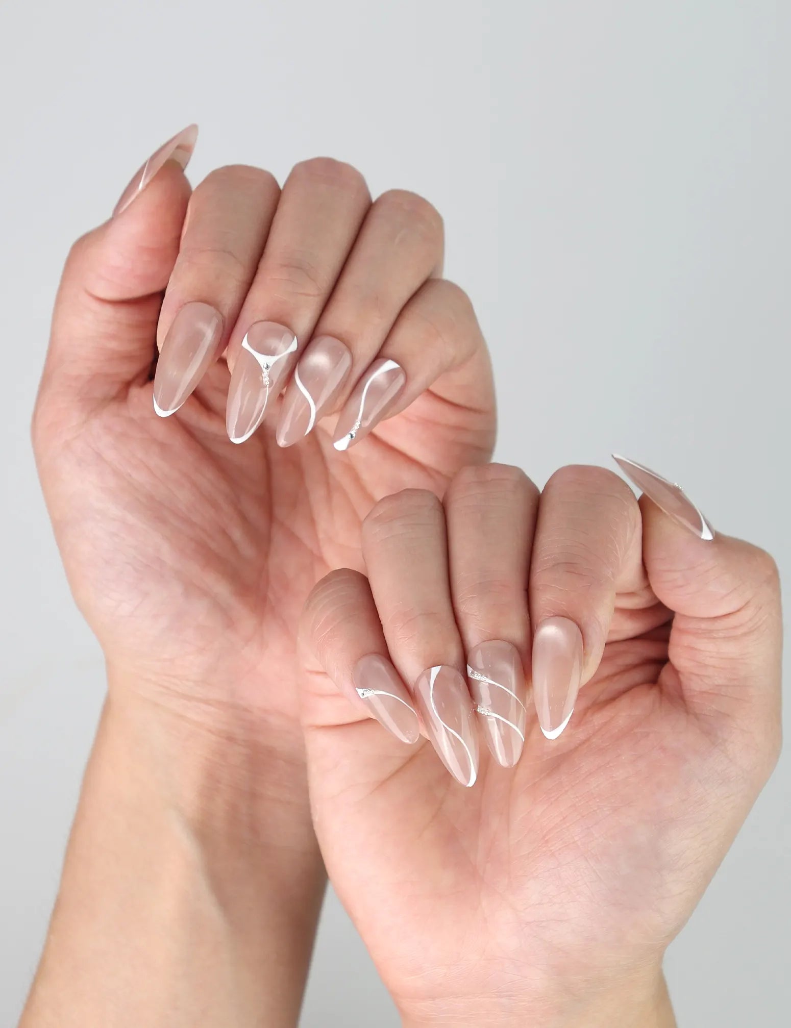 Side view of almond taupe nails with elegant swirl designs and fine golden highlights