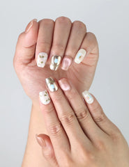 Close-up of Naillover’s handmade nails in soft pink featuring delicate painted flowers and glowing iridescent accents