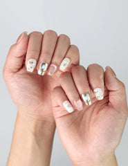 Side view of short square press-on nails with white floral details and a luminous shimmer effect