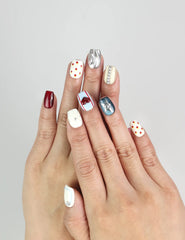 Hand wearing Vibrant Pop Singapore press-on nails with ivory base, red lips, silver buttons, and polka dots.