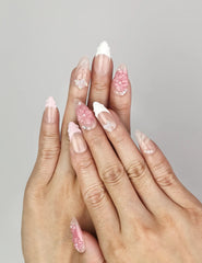 Hand wearing Naillover Whispering Petals in Pink Haze handmade press on nails with 3D blossoms and butterfly charms.