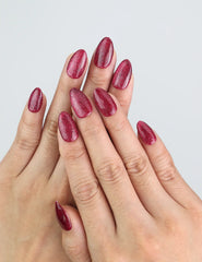 Model wearing Wine Illusion red almond press on nails by Naillover, featuring cat eye shine.