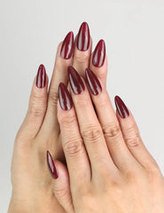 Model wearing Wine Velvet deep red almond Singapore press on nails by Naillover, showing the glossy finish in a relaxed hand pose.