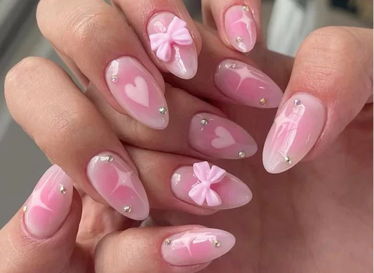 Close-up of coquette nails featuring soft pink base, 3D bows, and pearl accents – 2025 romantic nail trend.