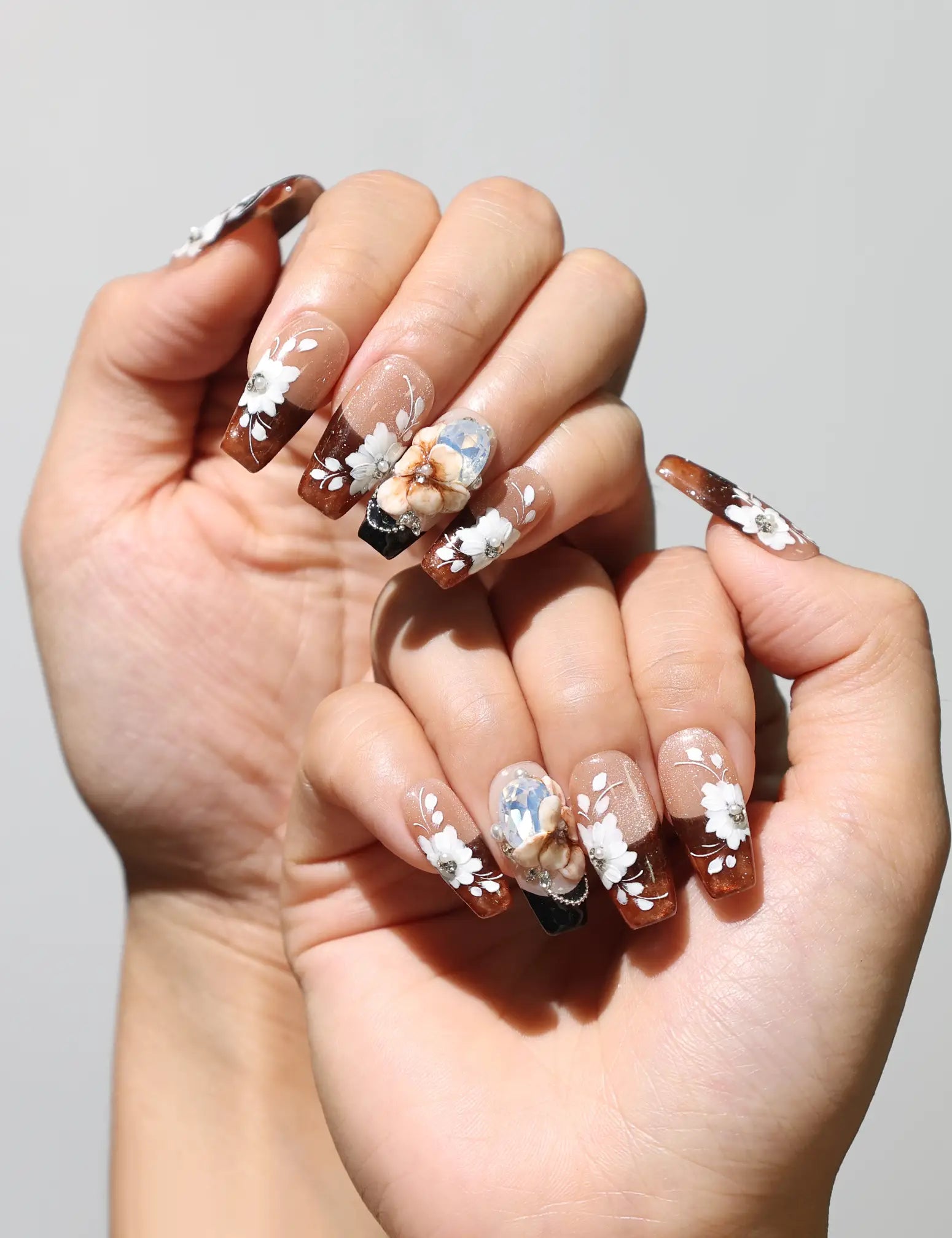 Amber Bloom classic nails style with amber gradient and white flower accents worn on hand