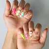 Side view of handmade Singapore nails in fresh fruit tones with tiny apple illustrations and nature-themed embellishments