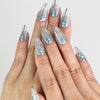 Hand wearing Aqua Wave Singapore press on nails with shimmering wave patterns in natural light
