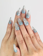 Hand wearing Aqua Wave Singapore press on nails with shimmering wave patterns in natural light