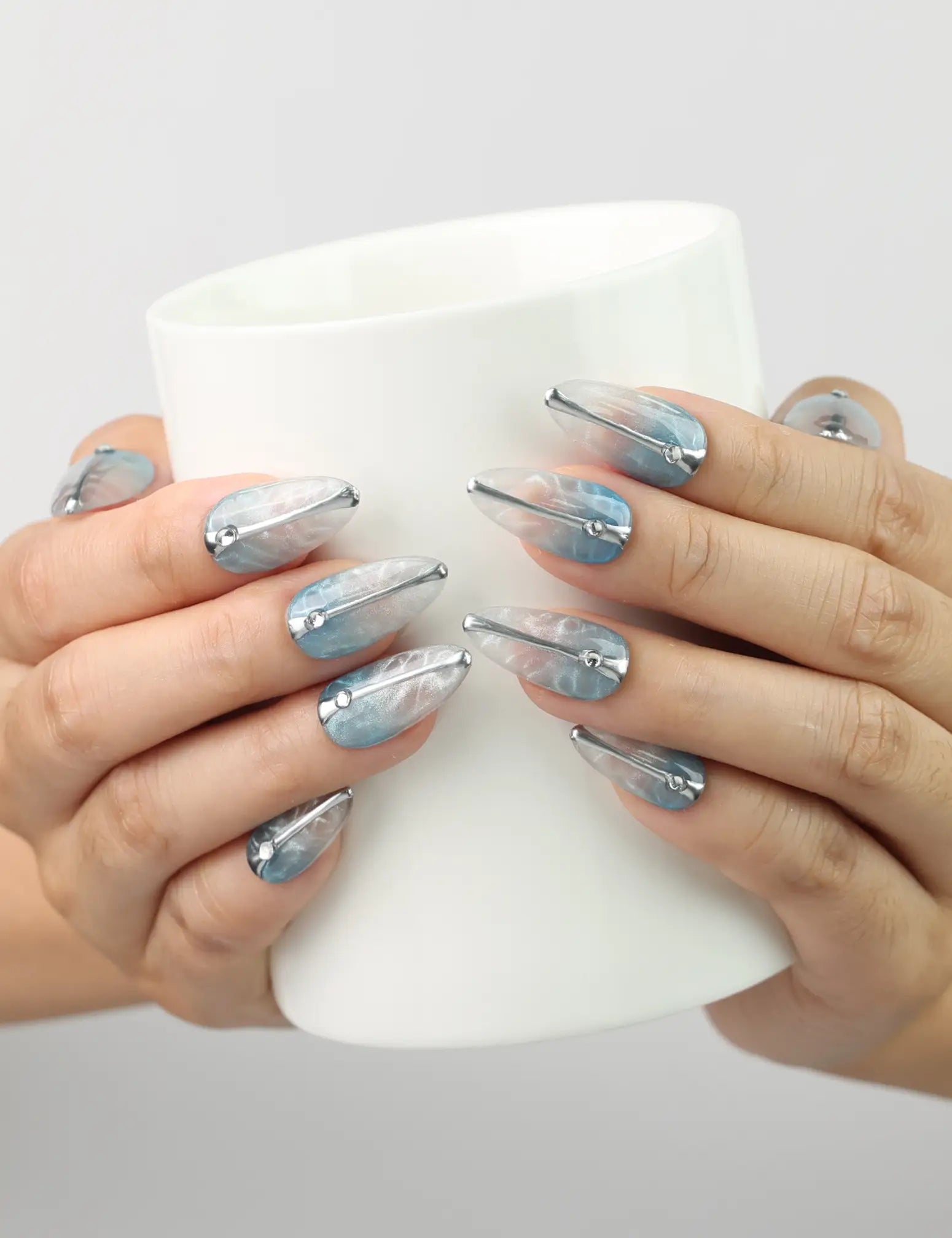 Hand holding a drink while wearing Aqua Wave Singapore press on nails with shimmering aquatic design