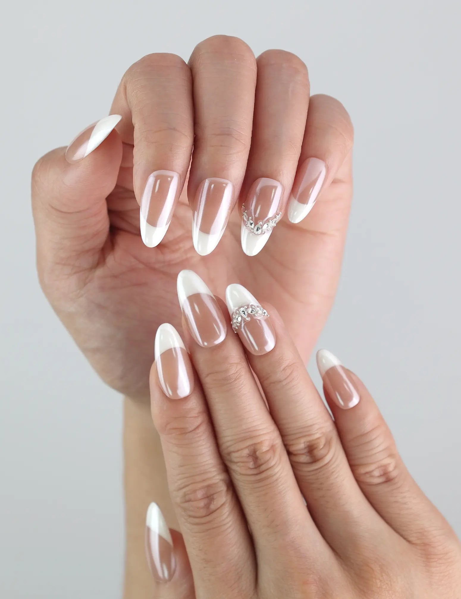 Close-up of Naillover’s handmade ombré nails in pink and white with elegant crystal embellishments