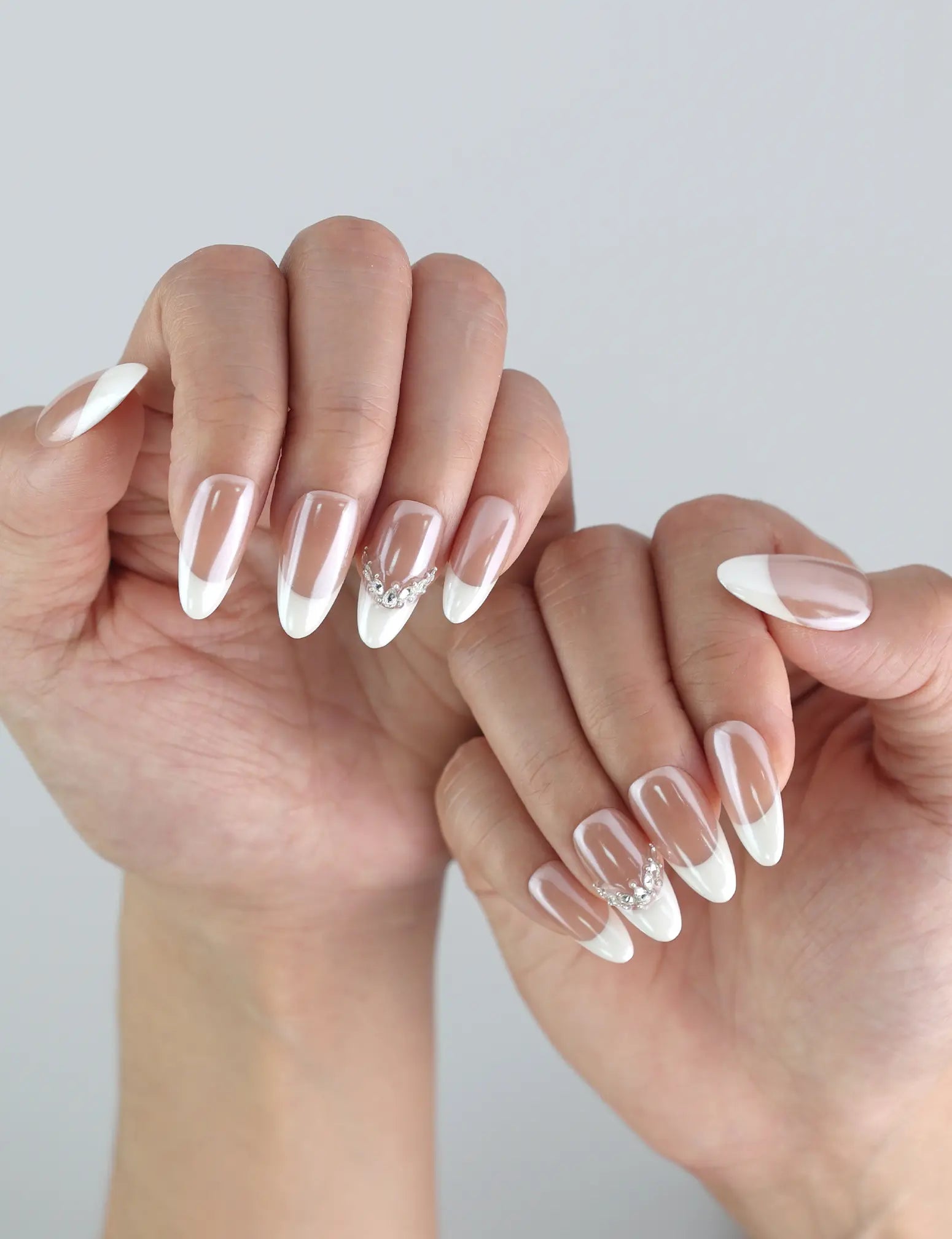 Side view of pastel pink gradient nails in almond shape with glossy finish and rhinestone detailing