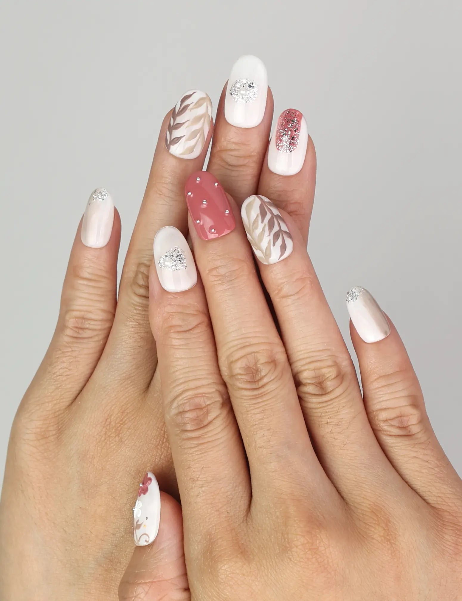 Hand wearing Naillover Autumn Floral Sparkle handmade press on nails featuring autumn floral patterns and glitter leaf details.