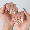 Side angle of sharp stiletto nails with animal print flair, raised flower details, and shimmering crystal touches
