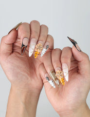 Side angle of sharp stiletto nails with animal print flair, raised flower details, and shimmering crystal touches