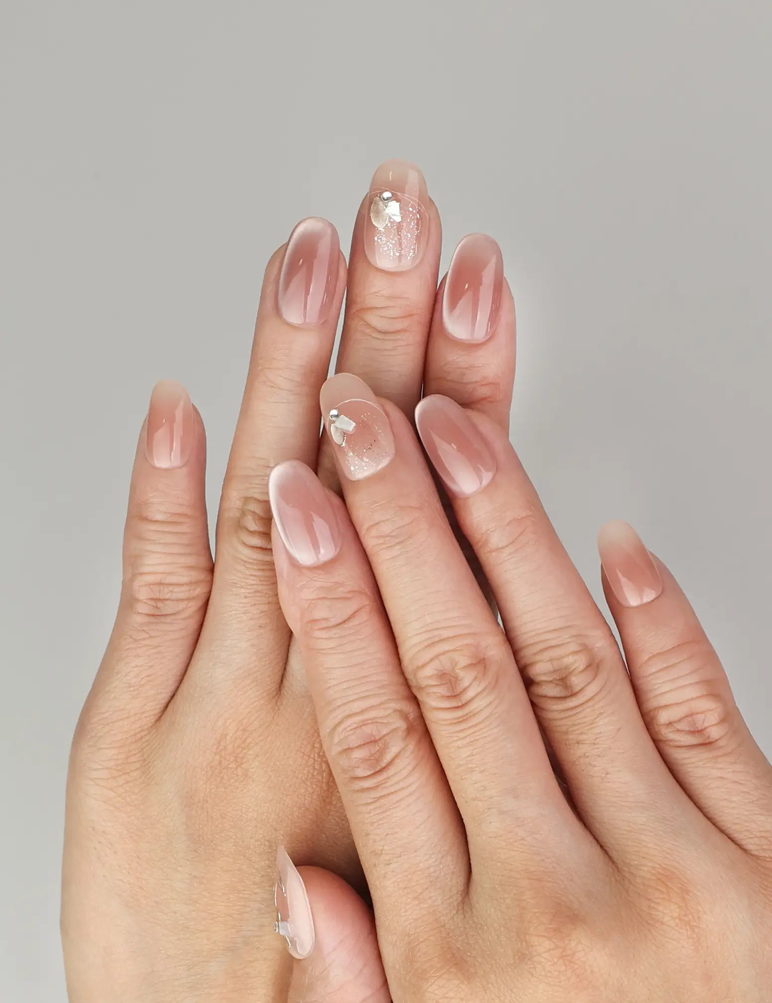Hand wearing Naillover Autumn Whisper handmade press on nails in nude-to-brown ombre with delicate gold foil accents.