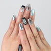 Hand model wearing square-shaped black press-on nails with metallic balloon dog sculptures and iridescent pop art accents