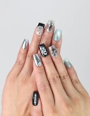 Hand model wearing square-shaped black press-on nails with metallic balloon dog sculptures and iridescent pop art accents