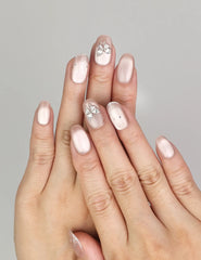 Hand wearing Naillover Beige Elegance handmade press on nails with shimmering cat eye finish, silver butterfly charms, and glitter stripe details.
