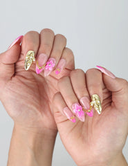 Side view of short pink press-on nails with glistening finish, delicate flower art, and mixed pearl-star charm arrangement