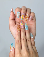 Close-up of Naillover’s handmade summer nails with 3D flower designs, ocean shell details, and soft beach tones