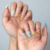 Side view of beachy almond nails with pastel pink blossoms, pearlescent texture, and sea-themed accents