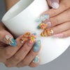 Hand holding a cup, showcasing Naillover’s coastal-inspired press-on nails with flower, shell, and starfish motifs