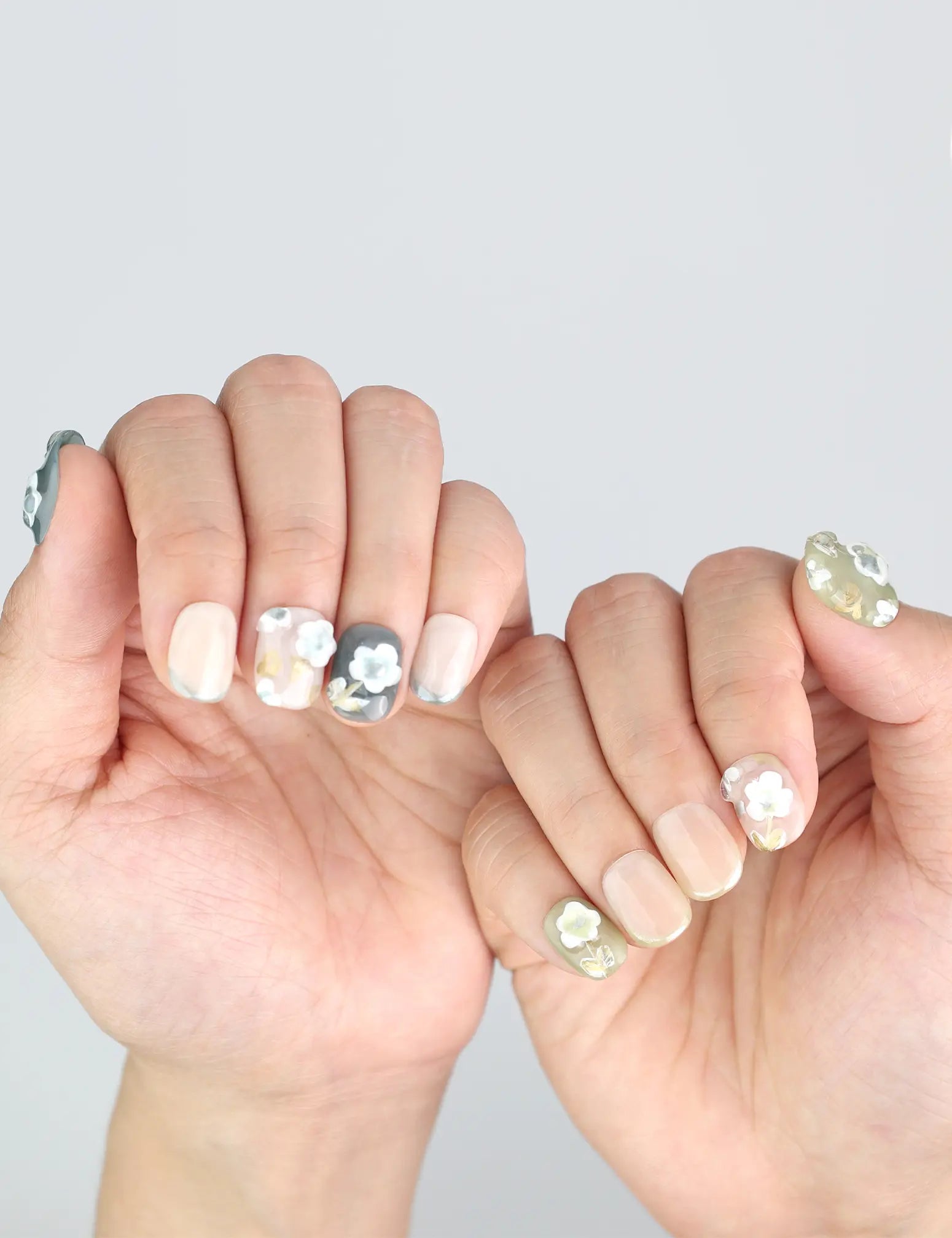 Hands spread to display Naillover’s handmade floral press on nails with olive and nude French fade blend