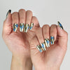 Model hand showcasing Blue Aura Singapore press on nails, featuring golden sheen and detailed butterfly accents.