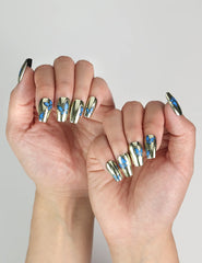 Model hand showcasing Blue Aura Singapore press on nails, featuring golden sheen and detailed butterfly accents.