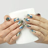 Hand holding a cup while wearing Blue Aura Singapore press on nails by naillover, highlighting golden sheen and butterfly details.