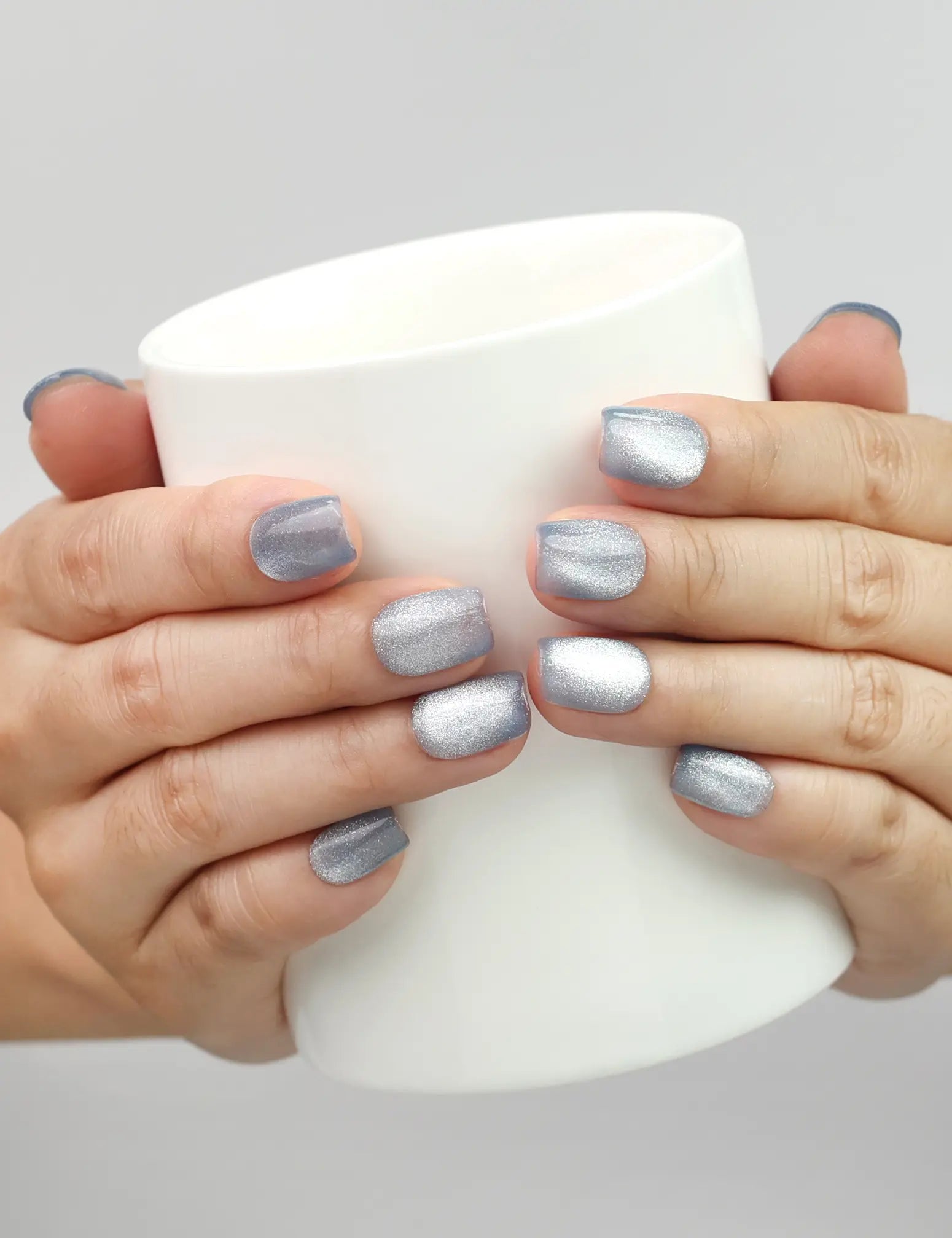 Blue Luster handmade cat eye press on nails from Naillover shown holding a glass, elegant nail styling