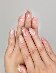 Hand wearing Naillover Bunny Blush handmade press on nails in soft pink with rabbit and floral designs accented by gold details.