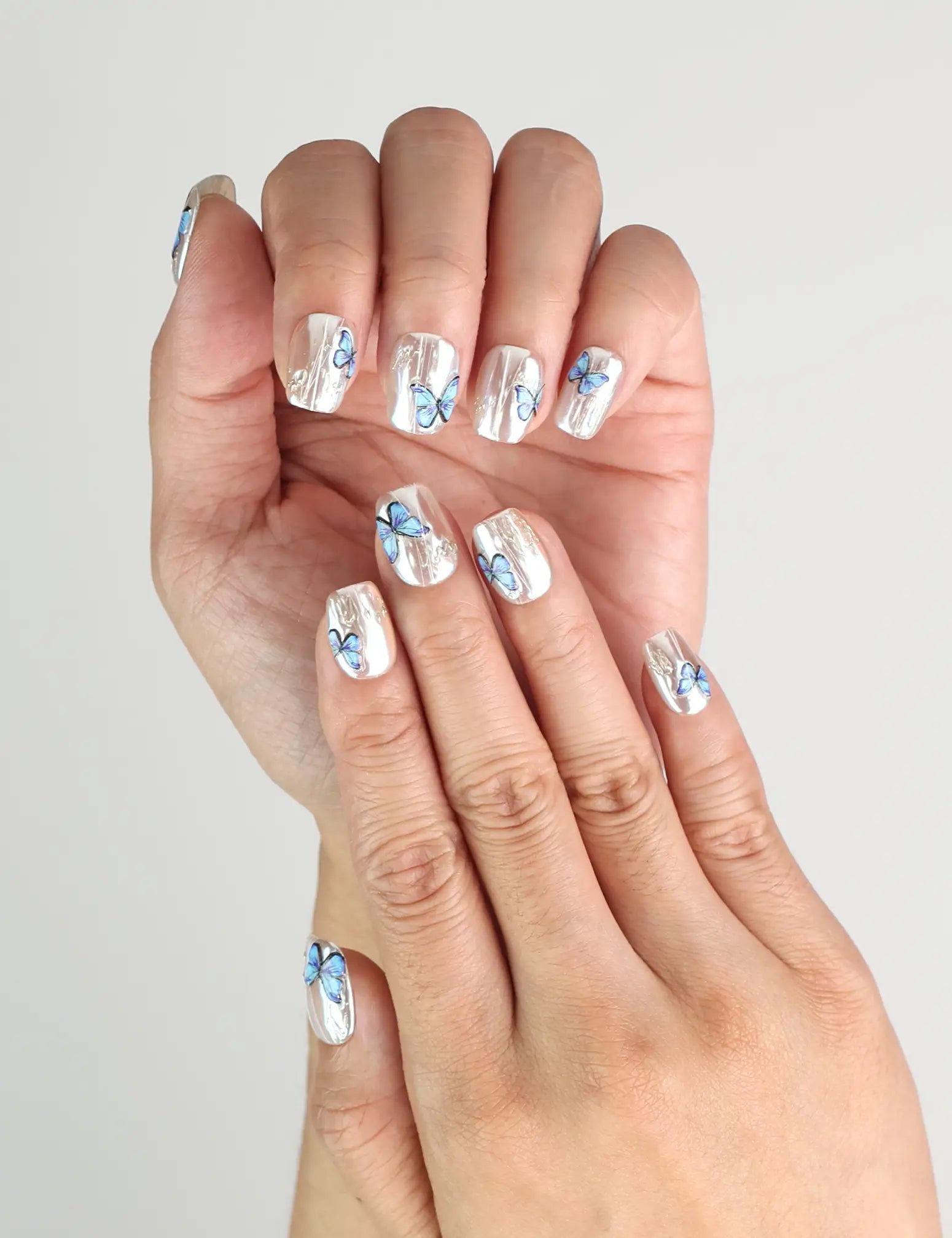 Close-up of Butterfly Light short press-on nails featuring vivid blue butterfly accents, handmade in Singapore by Naillover.
